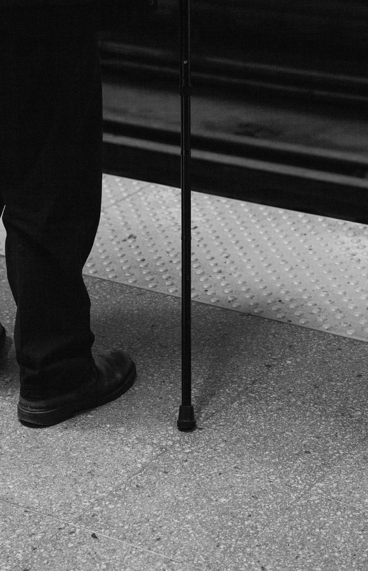 A person using a cane to climb stairs while holding onto a handrail