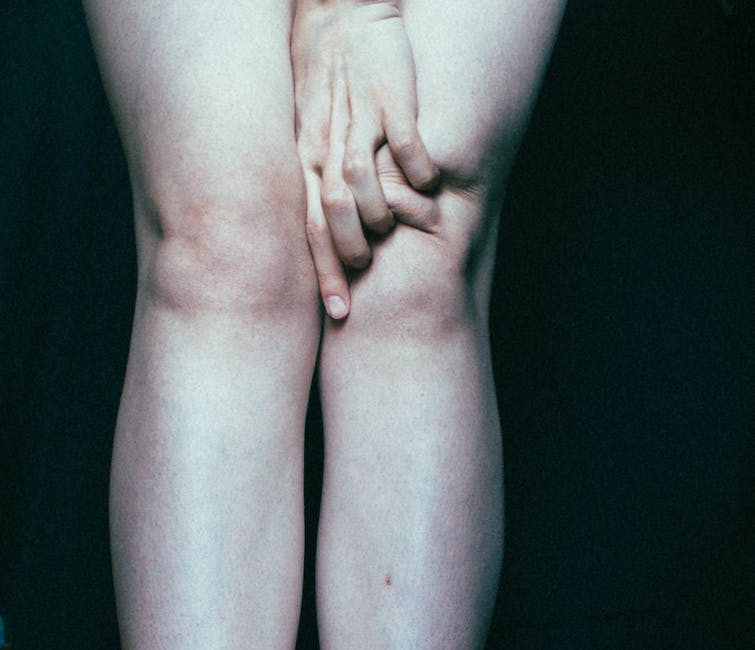 An image of a person holding their knee with a red zone on the area where it hurts.